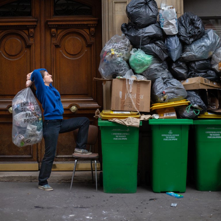 Una mujer intenta colocar basura en la calle.