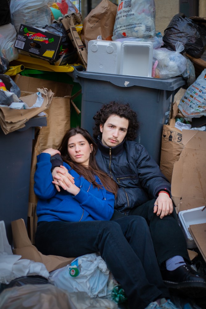 Una pareja posa con basura en el fondo.