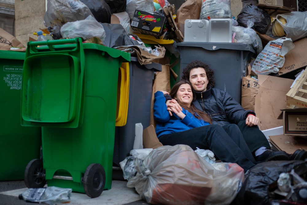 Dos personas sentadas sobre la basura en las calles de Paris