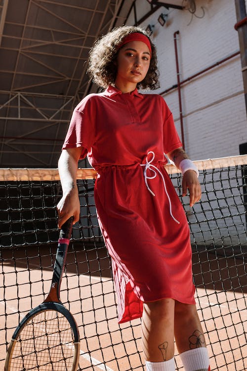 Una chica viste ropas deportivas con una raqueta de tenis