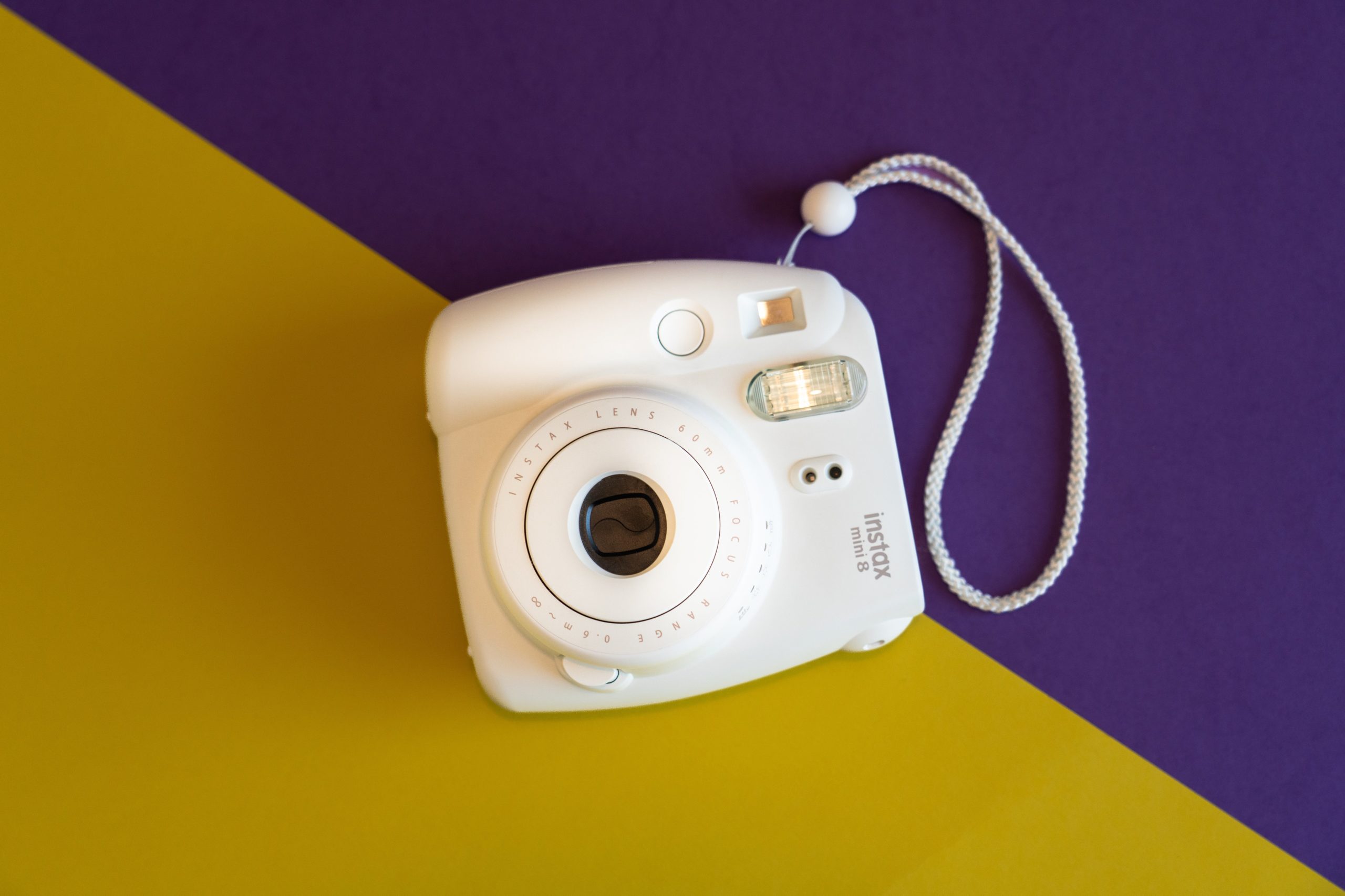 Instax de Fujifilm fondo amarillo y morado.