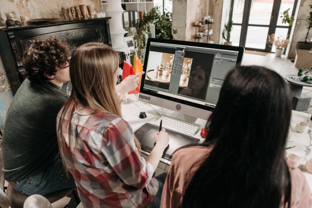 Tres personas miran la pantalla de computadora mostrando una imagen siendo editada en un software profesional.